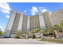 Exterior view of a high-rise condo building with palm trees and a clear blue sky at 4800 S Ocean Blvd. # 514, North Myrtle Beach, SC 29582