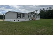 Well-maintained mobile home on a spacious lot featuring gray siding and black shutters at 71 Mohican Dr., Georgetown, SC 29440