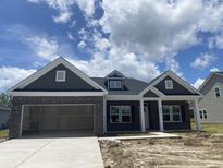 Charming single-story home featuring a brick facade, attached garage, and well-lit entryway, all under a cloudy sky at 1014 Black Locust Pl., Longs, SC 29568