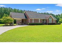 Charming brick home with manicured lawn, attached carport, and mature tree in a desirable neighborhood at 1752 Patriot Ct., Mullins, SC 29574