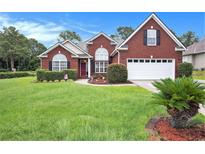 Charming red brick home with manicured lawn, shrubs, and a two-car garage, complete with a well-maintained landscape at 203 Old Hickory Dr., Conway, SC 29526