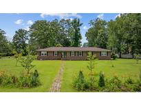 Charming brick home features a well-manicured lawn with landscaped flower beds and a brick walkway at 300 Crescent Dr., Conway, SC 29526