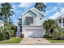 Charming two-story home with blue siding, a two-car garage and lush landscaping with palm trees at 305 Splendor Circle, Murrells Inlet, SC 29576