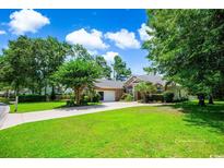 Charming brick home featuring a well-manicured lawn, mature trees, and a spacious driveway at 4499 Firethorne Dr., Murrells Inlet, SC 29576