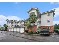 Exterior view of condo complex with attached garages and palm trees on a cloudy day at 4868 Dahlia Ct. # 202, Myrtle Beach, SC 29577