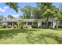 Charming single-story home with lush lawn, mature trees, and stylish black shutters at 520 13Th Ave. N, Surfside Beach, SC 29575