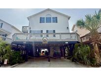 Two story beach home with a sign, white siding, and covered parking with a golf cart underneath at 6001-B5 S Kings Hwy., Myrtle Beach, SC 29575