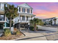Charming elevated beach house with covered parking, and a sunset colored sky at 611 N Ocean Blvd., Surfside Beach, SC 29575