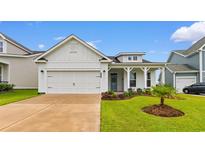 Charming white home featuring a manicured lawn, two-car garage and covered porch, perfect for relaxed living at 908 Pelagic Loop, Myrtle Beach, SC 29579