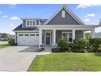 Charming home featuring a two-car garage, manicured lawn, and inviting front porch with decorative columns at 914 Mary Read Dr., North Myrtle Beach, SC 29582