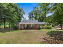 Charming brick home featuring a cozy front porch and a well-maintained lawn, nestled among mature trees at 1217 S Highway 501, Marion, SC 29571