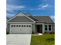 Charming single-story home features a two-car garage, gray siding, and a well-manicured lawn under a clear blue sky at 1514 Saw Palmetto St., North Myrtle Beach, SC 29582