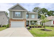 Charming two-story home with a two car garage, stone accents, manicured lawn, and a well-lit porch at 160 Juniata Loop, Little River, SC 29566