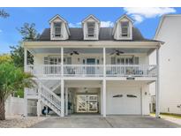 Charming two-story beach home featuring a spacious covered porch, white picket railings, and well-maintained landscaping at 1725 26Th Ave N, North Myrtle Beach, SC 29582