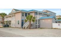 Charming two-story beach home featuring gray wood siding, a blue metal roof, and multiple elevated deck spaces at 202 27Th Ave. N, North Myrtle Beach, SC 29582