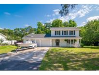 Charming two-story home with blue shutters, covered porch, two car garage, and a boat on the driveway at 66 Johnstone Ln., Georgetown, SC 29440