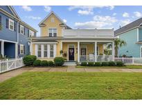 Charming two-story yellow home with a white picket fence and well-manicured landscaping at 721 Mckinley Way, Myrtle Beach, SC 29577