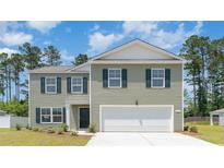 Charming two-story home featuring a two-car garage, gray siding, and green shutters against a backdrop of trees and a blue sky at 743 Chazen Way, Longs, SC 29568