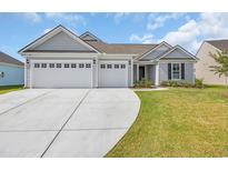 Charming single-story home featuring a three-car garage and manicured lawn under a bright, partly cloudy sky at 1121 Oxeye St., North Myrtle Beach, SC 29582