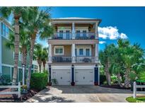 Stunning beachfront home featuring double balconies and a two-car garage nestled among lush palm trees at 1473 Basin Trail, Murrells Inlet, SC 29576