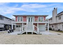 Charming raised beach house with white stairs, a garage, and a waterfront view at 25 Newport St., Ocean Isle Beach, NC 28469