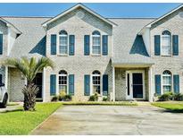 Charming brick townhouse featuring blue shutters, well-maintained landscaping, and a concrete driveway at 3978 Tybre Downs Circle # 3978, Little River, SC 29566