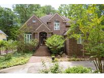 Charming brick home featuring mature trees, landscaped yard, and a welcoming front entrance at 469 White Heron Ct. Sw, Sunset Beach, NC 28468