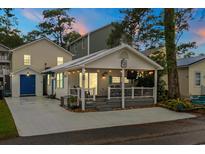 Charming beach house featuring a spacious porch with outdoor seating, string lights, and a well-maintained yard at 6001-1680 S Kings Hwy., Myrtle Beach, SC 29575