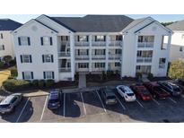 Three-story condo building with white siding and blue shutters surrounded by mature landscaping and parking lot at 901 West Port Dr. # 712, North Myrtle Beach, SC 29582