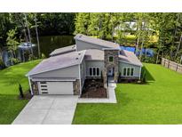 Stunning home with modern design, lush landscaping, and a serene pond view, enhancing its curb appeal at 1028 Colette Ct, Conway, SC 29526