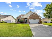 Charming brick home with a manicured lawn, colorful flower beds, and a two-car garage at 107 Fox Den Dr., Murrells Inlet, SC 29576