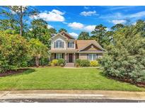 Charming two-story home with stone accents, lush landscaping, and a well-manicured lawn at 128 Knotty Pine Way, Murrells Inlet, SC 29576
