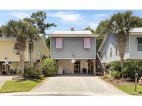 Charming coastal home featuring pink shutters, a metal roof, and a low maintenance gravel driveway at 147 Weatherboard Ct., Pawleys Island, SC 29585