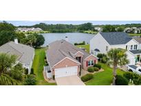 Beautiful brick home with lush landscaping, an attached garage, and a tranquil lake view at 2210 Haystack Way, Myrtle Beach, SC 29579