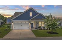 Charming home with blue and tan siding, a well-manicured lawn, and a blossoming tree, perfect for curb appeal at 264 Switchgrass Loop, Little River, SC 29566
