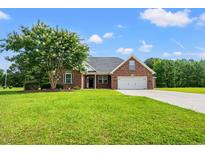 Charming brick home with a two-car garage, manicured lawn, and mature landscaping at 307 Russ Rd., Loris, SC 29569