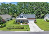 Charming brick home featuring a landscaped front yard, a covered porch, and a two-car garage at 4536 Fringetree Dr., Murrells Inlet, SC 29576