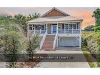 Charming two-story beach home with a inviting front porch and a convenient ground-level garage at 5 Tiara Ln., Murrells Inlet, SC 29576