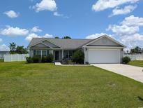 Charming single-story home with a well-manicured lawn and attached two car garage at 671 American Beech St., Loris, SC 29569
