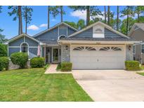 Charming home featuring a two-car garage, manicured lawn and low foundation shrubbery at 890 Knoll Dr., Little River, SC 29566