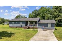 Charming single-story home features a cozy front porch, a well-manicured lawn, and a side driveway at 903 N Park St. Ext., Mullins, SC 29574