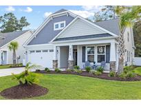 Charming home with a two-car garage, stone accents, manicured lawn, and a cozy front porch with seating at 212 Starlit Way, Myrtle Beach, SC 29579