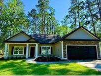 Inviting home featuring a well-manicured lawn and an attached two-car garage with a stone facade at 3216 Hugo Rd., Conway, SC 29527