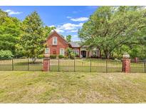 Charming brick home with lush landscaping and a decorative black metal fence at 487 Trestle Way, Conway, SC 29526
