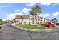 Inviting condo complex with manicured lawn, palm trees, and ample parking spaces at 5601 N Ocean Blvd. # A309, Myrtle Beach, SC 29577