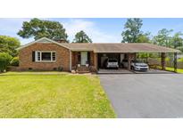 Charming brick home featuring a well-maintained lawn, a covered two car carport, and classic architectural details at 6204 Sancindy Ln., Myrtle Beach, SC 29572