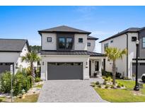Two-story home featuring a gray garage door, black trim, well-manicured lawn, and beautifully landscaped front yard at 6706 Ocean Breeze Loop, Myrtle Beach, SC 29572