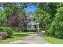 Charming two-story home with lush landscaping, mature trees, and a long driveway leading to the house at 100 Brookgreen Trace Pl., Pawleys Island, SC 29585
