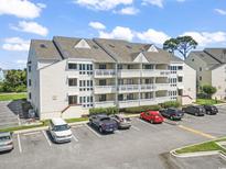 Three-story condo building with ample parking and balconies against a blue sky with fluffy white clouds at 1100 Possum Trot Rd. # F218, North Myrtle Beach, SC 29582