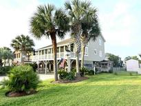 Charming beach house featuring a large deck and manicured lawn with mature palm trees at 404 29Th Ave. N, North Myrtle Beach, SC 29582